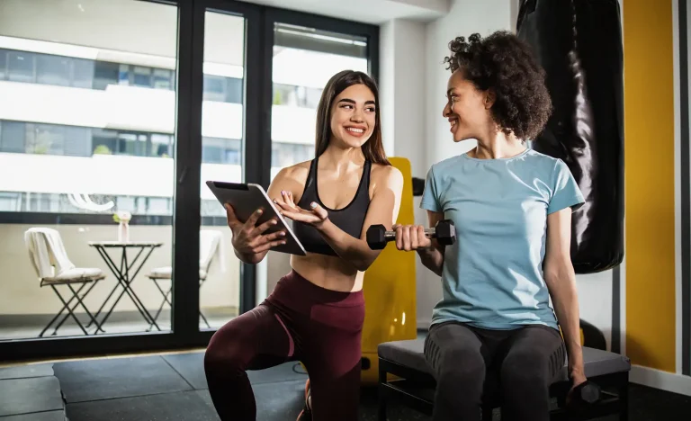 Instructor showing training results on the tablet to her client in the gym