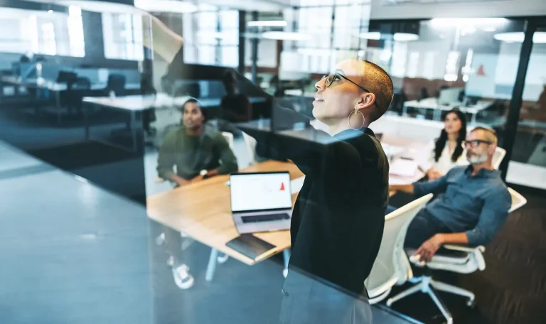 woman pointing to glassd board in planning meeting