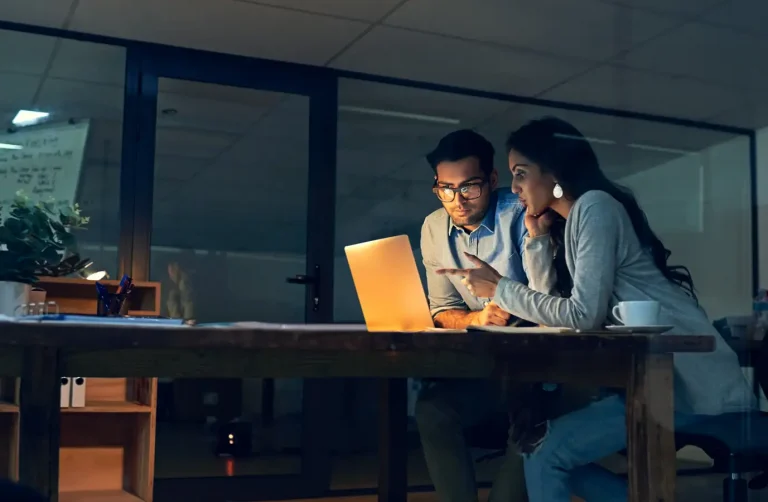 Cropped shot of two colleagues working late on a laptop in an office