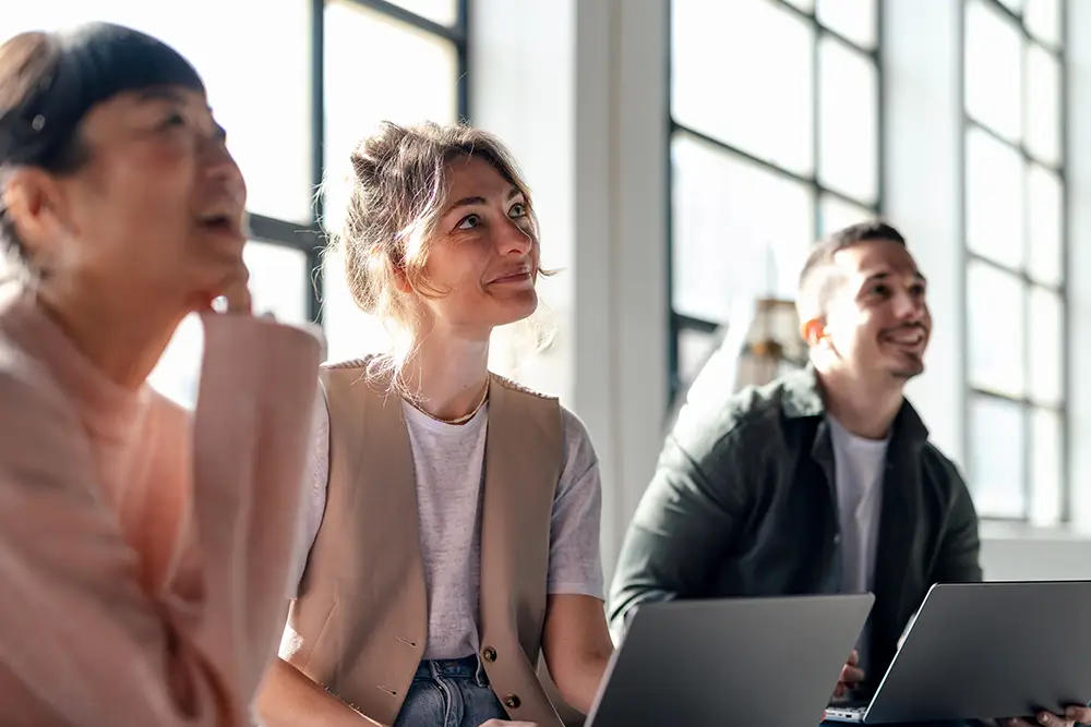 Colaboradores envolvidos em um projeto colaborativo em um espaço de trabalho compartilhado bem iluminado, incorporando trabalho em equipe e comunidade.